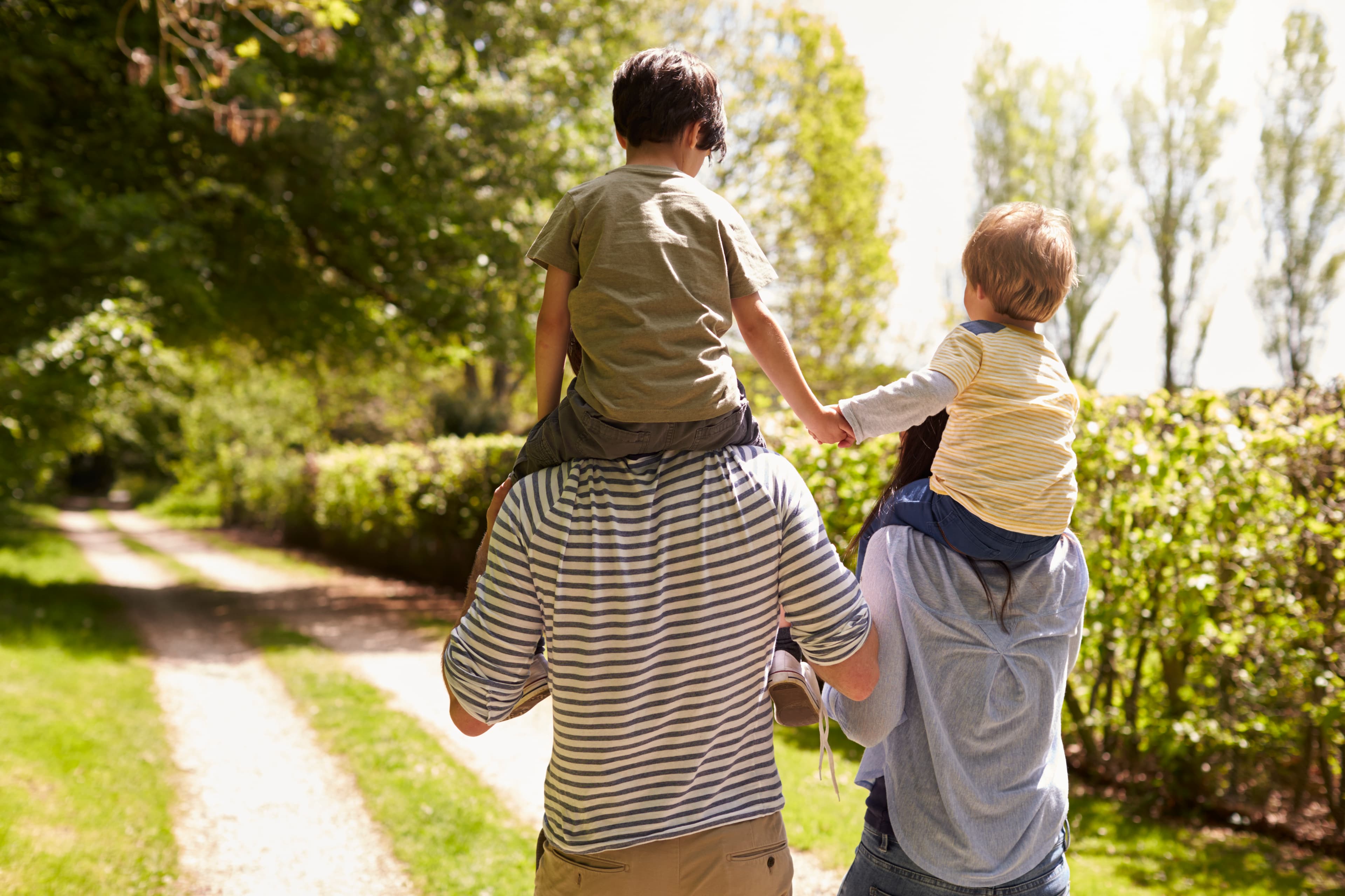 Parent carrying child piggyback through nature